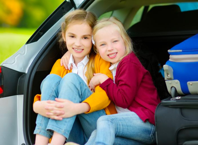 Sibling girls sitting in the back of a car hugging