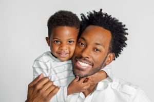 portrait of black man with his young son smiling, happy, hugging