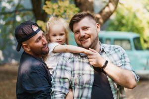 happy same sex male couple carrying their daughter