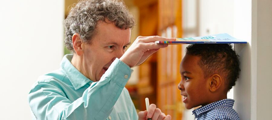 Father measuring the height of is son against the wall