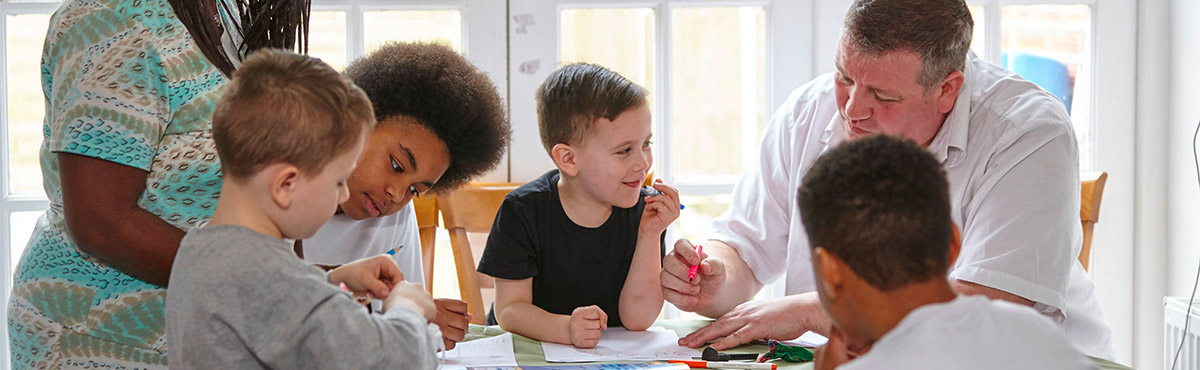 Family of six sitting at a dining room table doing homework