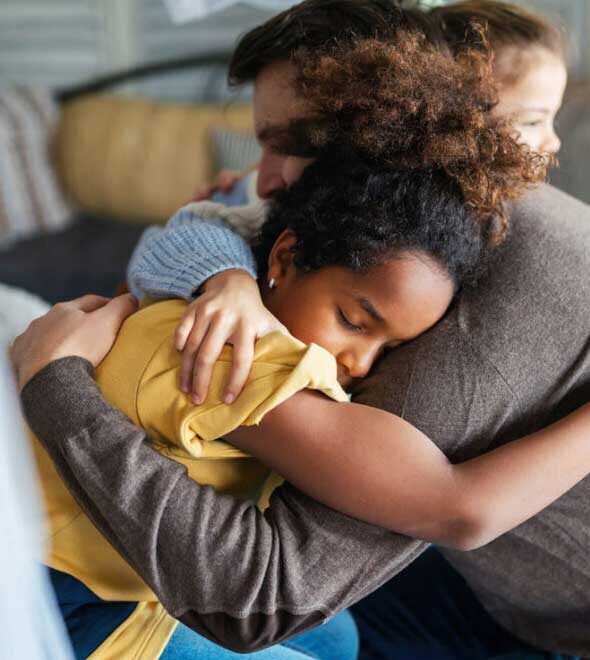 Happy family. Smiling father with disability in wheelchair hugging with children at home